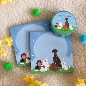 Puede incluir: Dos blocs de notas azules con un borde blanco y un dise&ntilde;o de perros sobre un fondo de nubes. Los blocs de notas miden 15 mm x 10 m. El dise&ntilde;o incluye un perro blanco y negro, un perro marr&oacute;n y blanco, un perro blanco, un perro negro, un perro marr&oacute;n y un perro blanco. Los blocs de notas est&aacute;n sobre una superficie blanca y peluda.