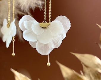 May include: A pair of delicate white flower earrings with gold chain and bead accents. The earrings are made of dried flower petals and have a delicate, feminine look.