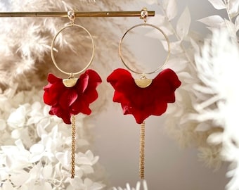 May include: A pair of gold hoop earrings with red flower accents and dangling gold chains.
