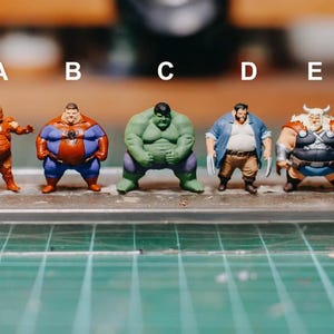 以下が含まれることがあります： アイアンマン、スパイダーマン、ハルク、ウルヴァリン、ソーを含む5体のスーパーヒーローフィギュアのコレクション。各フィギュアは、誇張されたプロポーションと鮮やかな色で漫画風に描かれています。フィギュアは透明な長方形のベースに展示されています。