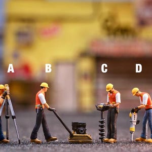 May include: Miniature construction workers in orange vests and yellow hard hats operate various tools. One uses a surveying instrument, another a compactor, a third a drill, and the last a jackhammer. The scene is set outdoors with a blurred background.