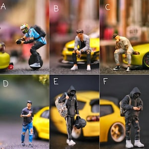 May include: Miniature figurines of people in various poses, including a person riding a unicycle, and people sitting or standing near yellow sports cars. The figurines are detailed and realistic, with a focus on urban street style.