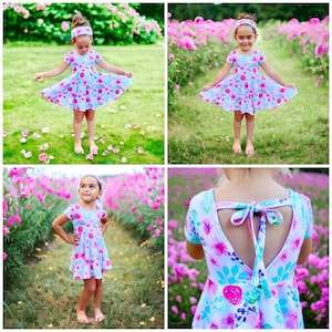 May include: A young girl wearing a light blue and pink floral print dress with a matching headband. The dress has a low back with a bow tie detail. The girl is standing in a field of pink flowers.