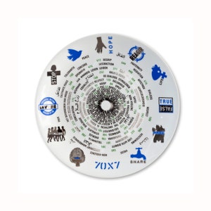 Puede incluir: Un plato de cerámica blanco con un diseño circular que presenta palabras como "Paz", "Esperanza" e "Igualdad" en varios idiomas. El plato tiene un patrón central en blanco y negro y varios símbolos.