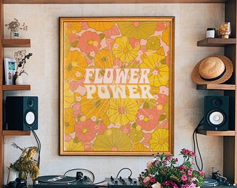 Könnte beinhalten: Ein Holztisch mit einer Vase mit rosa und violetten Blumen darauf. Der Tisch steht vor einer Wand mit einem Bücherregal und einem gerahmten Druck mit dem Text "Flower Power" in gelben Buchstaben auf einem rosa und gelben Blumenhintergrund.