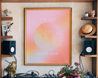 Könnte beinhalten: Ein Holztisch mit einer hellen Holzoptik steht in einem Raum mit einem Bücherregal, einem Plattenspieler und einem gerahmten Druck mit dem Text "less ego more soul".