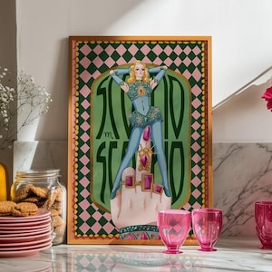 May include: A framed art print featuring a stylized illustration of a figure in a blue and green outfit with the text "1000 SCANDALS". The image is displayed on a marble countertop with pink glassware, plates, and a vase with flowers.