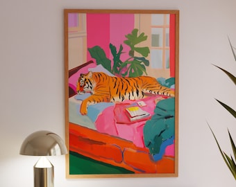 Puede incluir: Una ilustración enmarcada de un tigre acostado en una cama con una colcha estampada en rosa y verde. El tigre es naranja y negro con rayas blancas. Hay una planta en el fondo.