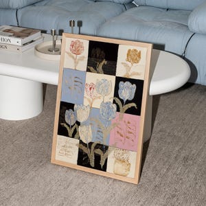 May include: A framed rectangular wall art piece featuring a grid of twelve squares, each displaying a stylized tulip illustration in various colors including blue, pink, black, and cream, set within a light-toned wooden frame.