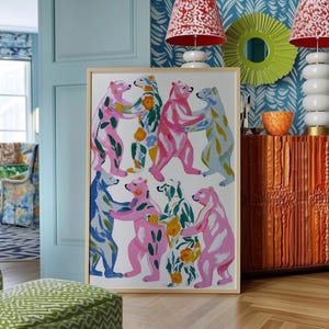 Puede incluir: Una impresión artística enmarcada que presenta una ilustración caprichosa de osos coloridos abrazándose. Los osos están pintados en tonos de rosa, azul y verde, con detalles florales. La obra de arte se exhibe en una habitación con una puerta azul y papel pintado estampado.