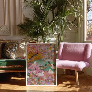 May include: A framed art print depicting a vibrant floral scene with ducks. The artwork is in a white frame and is displayed in a room with a pink chair and a large potted plant. The painting features a variety of colours, including pink, yellow, green, and blue.