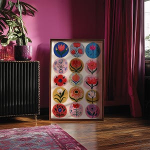 May include: Framed artwork featuring a collection of colorful floral designs in circular patterns. The artwork is displayed in a wooden frame, showcasing various flower illustrations in shades of red, blue, yellow, and pink. The artwork is set against a white background.