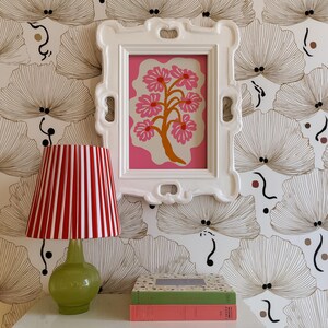 Flat-graphic illustration of a stylized orange tree trunk sprouting bright pink daisies on a cream blob shape against a vibrant pink background—cheerful, preppy and coquette-inspired.
