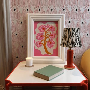 Flat-graphic illustration of a stylized orange tree trunk sprouting bright pink daisies on a cream blob shape against a vibrant pink background—cheerful, preppy and coquette-inspired.