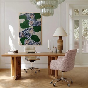 May include: A light wood desk with a cream-colored office chair and a pink patterned chair. A large framed painting of lions hangs on the wall. A wooden lamp with a cream shade and a glass chandelier are also visible.