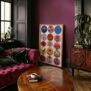 May include: A framed floral art print featuring colorful flower designs in circular patterns. The artwork is displayed in a room with a burgundy sofa, a wooden coffee table, and a dark-colored wall. The room is decorated with a cabinet and a window.