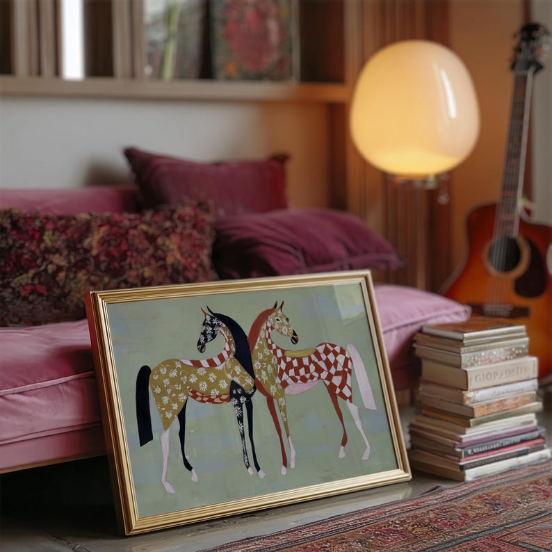 May include: A framed artwork featuring two stylized horses with patterned coats in gold, black, and red. The artwork is set against a light green background, with a gold frame. The scene includes a guitar, books, and a floor lamp.