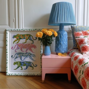 Four prowling leopards in vivid green, pink, sky-blue and indigo coats, each with whimsical floral patterns, stride across a cream backdrop. The bold dopamine palette enlivens living rooms, nurseries or eclectic gallery walls.
