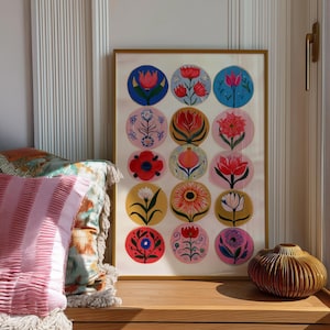 May include: A framed art print featuring colorful floral designs in circular patterns. The artwork showcases various flowers in shades of red, pink, blue, and yellow, set against different colored backgrounds. The frame is gold.