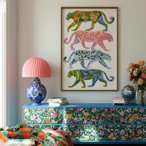 Four prowling leopards in vivid green, pink, sky-blue and indigo coats, each with whimsical floral patterns, stride across a cream backdrop. The bold dopamine palette enlivens living rooms, nurseries or eclectic gallery walls.