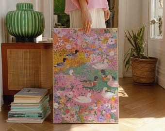 May include: A colorful painting featuring ducks in a floral landscape. The artwork showcases a variety of ducks amidst a vibrant array of pink, purple, and green flowers. The painting is held by a person wearing a pink top and white skirt.