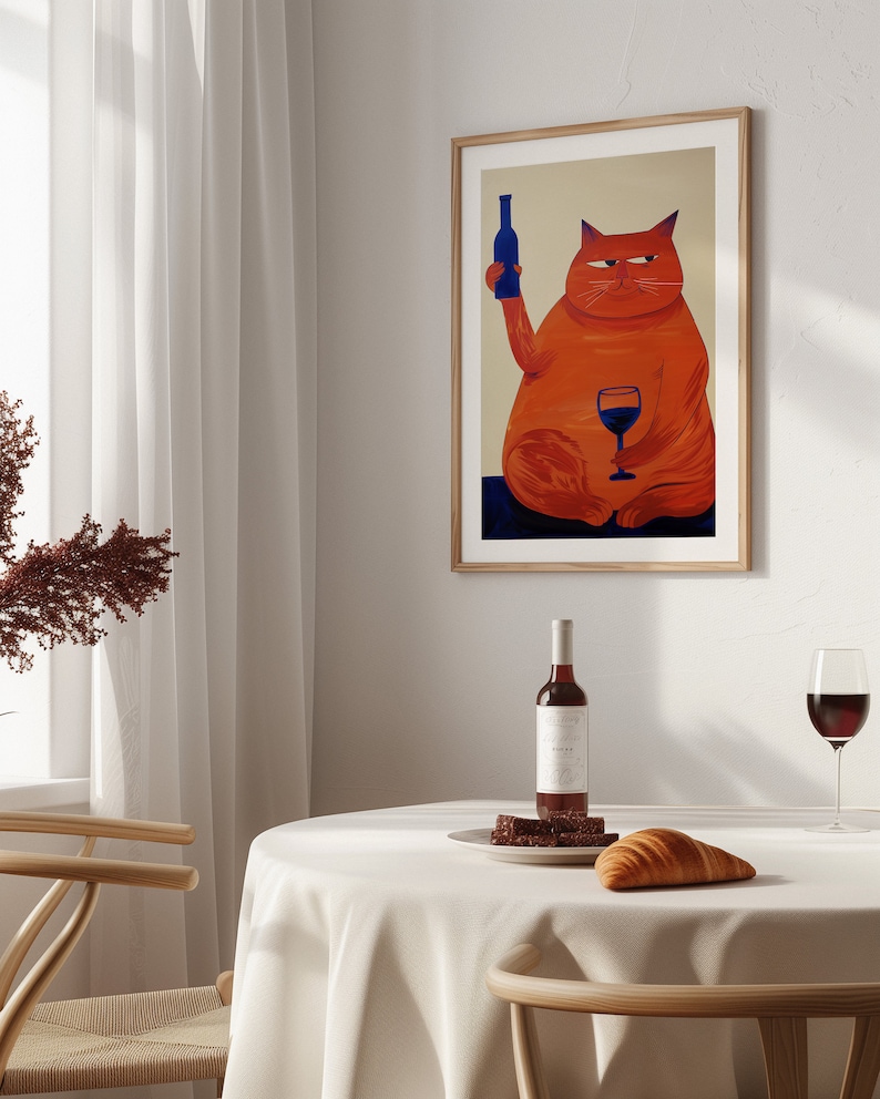 May include: A framed illustration of a red cat holding a bottle of wine in one paw and a glass of red wine in the other. The cat is sitting on a blue surface. The frame is made of wood and has a light brown finish.