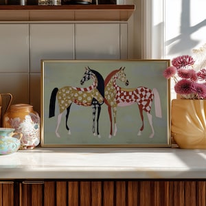 May include: A framed art print featuring two stylized horses. One horse has a black body with a white and black floral pattern, and the other has a red and white checkered pattern. The background is a light green color.