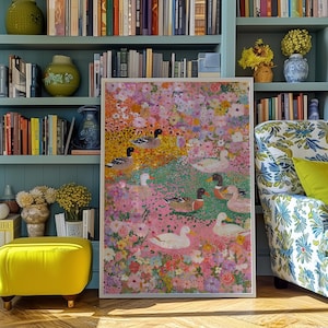 May include: A framed artwork depicting ducks amidst a colourful floral arrangement. The painting features a variety of flowers in pink, yellow, and white, with ducks dotted throughout. The artwork is displayed in a room with bookshelves and a patterned armchair.