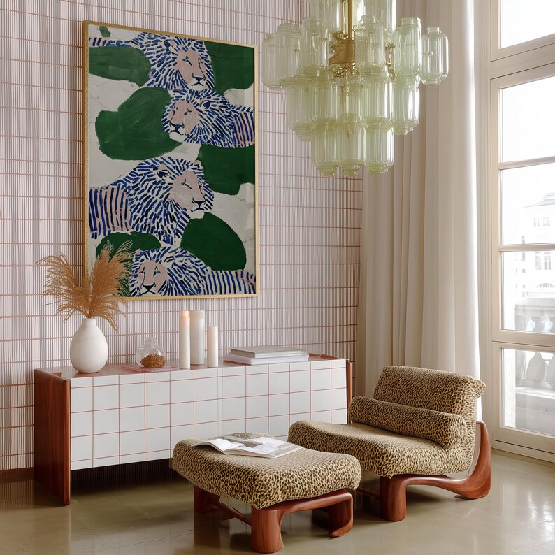 May include: An interior scene featuring a modern living room. A large framed artwork depicts lions with blue and white striped manes. A white cabinet with a tiled surface and red trim sits below the artwork. A leopard print chair and ottoman are in the foreground.