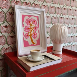 Flat-graphic illustration of a stylized orange tree trunk sprouting bright pink daisies on a cream blob shape against a vibrant pink background—cheerful, preppy and coquette-inspired.