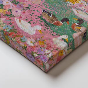 May include: A canvas print depicting a colourful floral scene with white and brown ducks. The artwork features a pink background with flowers and green patches. The ducks are positioned amongst the flowers.