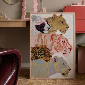 May include: A rectangular framed wall art print featuring four stacked big cat heads. The top cat is white with black geometric lines, the second is tan, the third is pink with red stripes, and the fourth is a spotted leopard above a blue-toned cat.