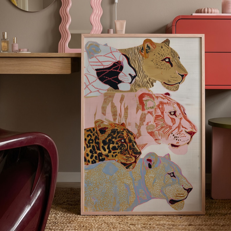 May include: A rectangular framed wall art print featuring four stacked big cat heads. The top cat is white with black geometric lines, the second is tan, the third is pink with red stripes, and the fourth is a spotted leopard above a blue-toned cat.