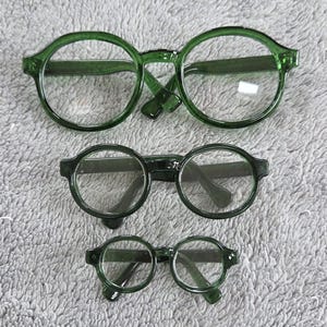 Helder groen omrande plastic poppenbril - ongeveer 9 cm/90 mm breed en 6,5 cm/65 mm breed