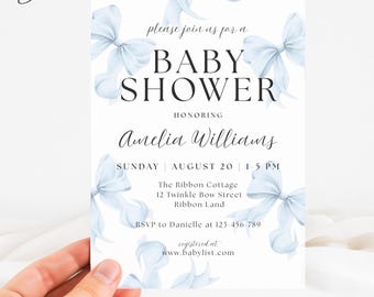 May include: A baby shower invitation with a white background and light blue watercolor bows. The invitation reads "Baby Shower" and includes details for the event, including the date, time, and location. The invitation is held by a hand.