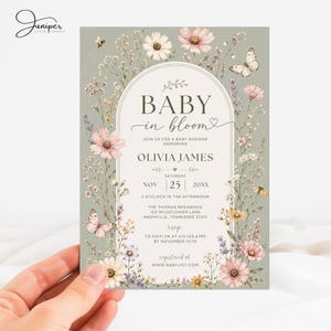May include: A sage green baby shower invitation card featuring an arched frame with floral illustrations of pink and white wildflowers, lavender, and butterflies. The text reads Baby in bloom, Olivia James, Saturday Nov 25 20XX, and event details.