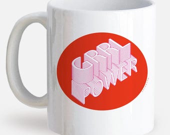 May include: White ceramic mug with a large red oval featuring the text "GRRL POWER" in a 3D-style, pink and white design. The mug has a curved handle and is suitable for hot or cold beverages.