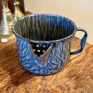 May include: A vintage blue and gray speckled enamelware pitcher with a strainer spout and a handle. The pitcher is made of metal and has a rustic look.