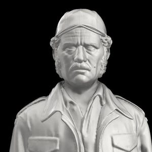 Puede incluir: Busto blanco de un hombre con gorra y chaqueta con cuello. La escultura tiene una expresión seria, con el ceño fruncido y bigote. El fondo es negro liso.