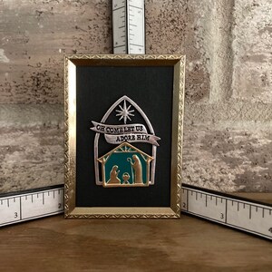 Small metal Nativity in gold frame.