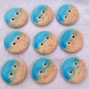May include: Ten round ceramic buttons with a blue and tan glaze. The buttons have two holes each.