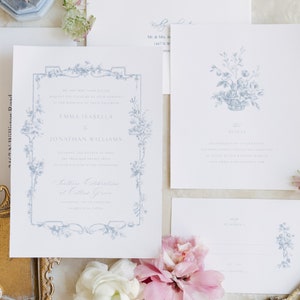 May include: A wedding invitation suite with a blue and white floral design. The invitation features a decorative border with a floral motif and the text "Emma Isabella to Jonathan Williams". The RSVP card features a floral design and the text "RSVP by March 1".