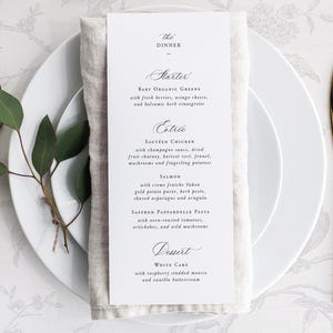 Peut inclure: Une carte de menu blanche avec une police d'écriture noire en script liste le menu du dîner : "The Dinner", "Starter", "Baby Organic Greens", "Entrée", "Sautéed Chicken", "Salmon", "Saffron Pappardelle Pasta", "Dessert", "White Cake".