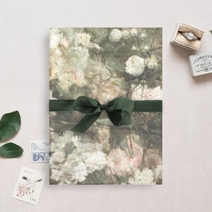 May include: A green ribbon tied in a bow on top of a floral patterned paper. The paper has a watercolor design of pink and white flowers.