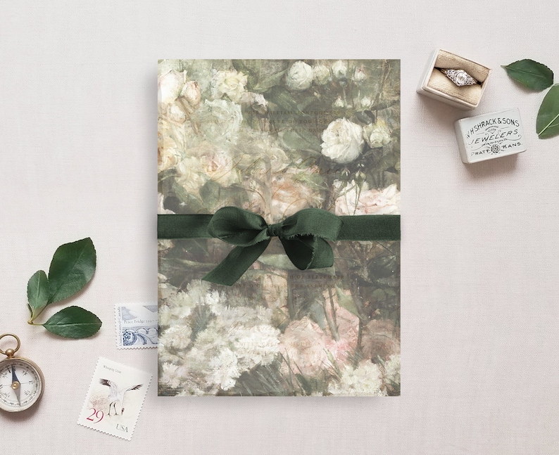 May include: A green ribbon tied in a bow on top of a floral patterned paper. The paper has a watercolor design of pink and white flowers.