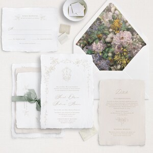Pu&ograve; includere: Suite di inviti di nozze con un design floreale sulla busta. L'invito presenta uno sfondo bianco con calligrafia dorata e uno stemma. La carta RSVP ha uno sfondo bianco con un bordo dorato. La carta dei dettagli ha uno sfondo rosa chiaro con calligrafia dorata.