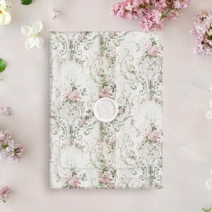 May include: A white envelope with a floral pattern and a wax seal. The envelope is surrounded by pink and white flowers.