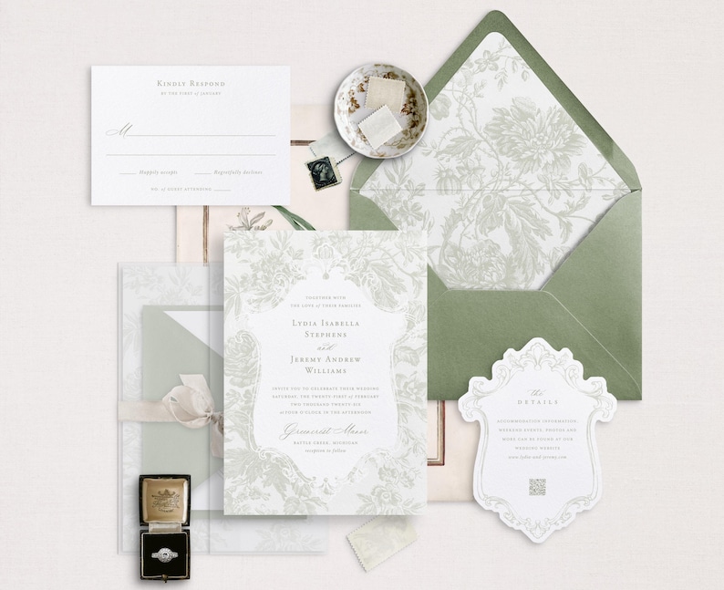 May include: A white wedding invitation with a floral design and the text "India Isabella Stephens and Jeremy Andrew Williams" in a grey font. The invitation is on a white background with a green envelope and a small white detail card.