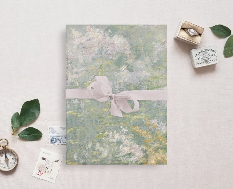 May include: A green and white patterned paper with a light pink ribbon tied in a bow. The paper is wrapped around a gift box. The box is sitting on a white surface.