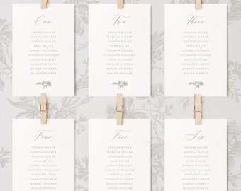 May include: Six white cards with black text, each labeled with a number from one to six. The cards list names for a wedding seating chart.